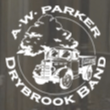 The logo for the a.w. Drybrook band, a white image on a grey background of an old fashioned coal lorry in front of a tree within a circular frame and the words a.w. Parker Drybrook band written around the outside of the circle