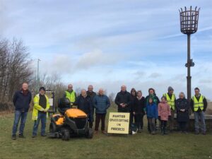 Group of people with the new tractor lawnmower and a sign that says pan Tod grass cutting in progress